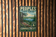 A vintage metal sign for the People's State Forest in Connecticut, featuring a scenic landscape with pine trees, a lake, and mountains.