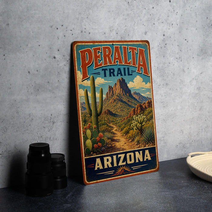 A vintage-style metal sign for the Peralta Trail in Arizona, featuring a desert landscape with cacti and mountains.