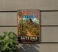 A vintage-style metal sign for the Peralta Trail in Arizona, featuring a desert landscape with mountains, cacti, and a dirt path.