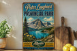 A vintage-style sign for Peter Lougheed Provincial Park in Alberta, Canada, featuring a scenic mountain landscape with a lake and pine trees.