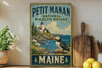 A vintage-style metal sign for the Petit Manan National Wildlife Refuge in Maine, featuring a lighthouse, puffins, and a coastal landscape.