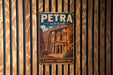 A vintage-style metal sign with the text "PETRA JORDAN" and an illustration of an ancient building, likely the Petra, is displayed on a wooden wall.