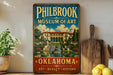 A vintage-style sign for the Philbrook Museum of Art in Oklahoma, featuring an illustration of a grand building with a fountain in the foreground.