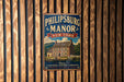 A vintage-style metal sign for the historic Philipsburg Manor in New York, featuring an illustration of a historic house surrounded by a wooden fence.