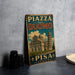 A vintage-style metal sign with the text "PIZZA DEL DUOMO PISA ITALY" and an illustration of the Leaning Tower of Pisa, indicating a location in Italy.