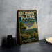 A vintage-style sign for Piedmont Plateau, Virginia, featuring a scenic landscape with a tree, a house, and a path.