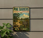 A vintage-style metal sign for Pine Barrens Cultural Landscape, featuring a scenic illustration of a forest and a winding path, mounted on a wall next to a plant.