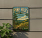 A vintage-style metal sign for Pine Hills Nature Preserve in Indiana, featuring a scenic landscape with a winding path and wildflowers.