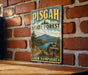 A vintage metal sign for Pisgah State Forest in New Hampshire, featuring a scenic landscape with mountains, pine trees, and a lake.