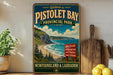 a vintage-style sign for Pistolet Bay Provincial Park, with a scenic coastal landscape and a wooden paddleboard.