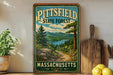 A vintage-style metal sign for the Pittsfield State Forest in Massachusetts, featuring a scenic landscape with pine trees, a lake, and mountains.