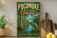 a vintage-style sign for the Pocomoke State Forest in Maryland, with a painting of a heron in the foreground. The sign also includes the text "Maryland's Natural Treasure".