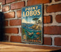 A vintage metal sign for Point Lobos State Marine Reserve in California, featuring an illustration of a rocky coastline, a seal, and a fish.