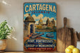 A vintage-style metal sign for Cartagena, Colombia, featuring a colorful illustration of the city's landmarks and a ship on the water.