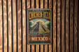 A vintage metal sign with a colorful illustration of a pyramid and a dragon, mounted on a wooden wall.