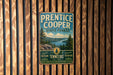 A vintage metal sign for Prentice Cooper State Forest, featuring a scenic image of pine trees, a river, and mountains.