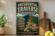 A vintage-style metal sign advertising the Presidential Traverse in New Hampshire, featuring a mountain landscape and directional signs.
