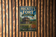 A vintage-style metal sign for Prickett's Fort State Park in West Virginia, featuring a wooden cabin and a flag.