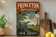 a vintage-style sign for Princeton Battlefield State Park, with a cannon and a scenic landscape in the background.