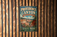 A vintage-style metal sign for Providence Canyon, a famous landmark in Georgia, hangs on a wooden wall.