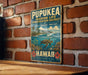 A vintage metal sign with a tropical beach scene and a turtle, mounted on a brick wall.