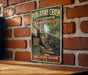 A vintage metal sign for the Purgatory Chasm State Reserve in Massachusetts, featuring a scenic image of a rocky trail leading up to a cliff.