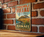 A vintage-style metal sign for Puukohola Heiau, the National Historic Site in Hawaii, is displayed on a brick wall.