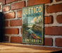 A vintage metal sign for Quetico Provincial Park in Ontario, featuring a scenic landscape with a lake, trees, and a canoe.