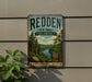 A vintage metal sign for the Redden State Forest in Delaware, featuring a scenic landscape with pine trees, a river, and mountains.