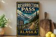 A vintage-style sign for the Resurrection Pass Trail in Alaska, featuring a scenic mountain landscape with a trail leading through it.