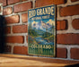 A vintage-style metal sign for the Rio Grande National Forest in Colorado, featuring a mountain landscape with pine trees and a river.
