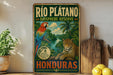 A vintage-style sign for the Rio Platano Biosphere Reserve in Honduras, featuring a colorful illustration of a parrot and a jaguar in a lush tropical forest.