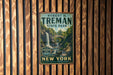 A vintage-style metal sign for Robert H. Treman State Park, featuring a scenic waterfall and forest landscape, is displayed on a wooden wall.