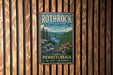 A vintage-style metal sign for Rothrock State Forest in Pennsylvania, featuring a scenic landscape with pine trees, a river, and pink flowers.