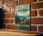 A vintage-style metal sign for Rothrock State Forest in Pennsylvania, featuring a scenic mountain landscape and the text "Pennsylvania Explore Hike Discover".