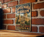 A vintage-style metal sign with the text "REAL MONASTERIO DE SANTAMARIA DE GUADALUPE ESPAÑA" is displayed on a brick wall.