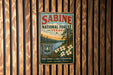 a vintage metal sign for Sabine National Forest in Texas, hanging on a wooden wall.