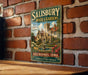 A vintage-style metal sign for Salisbury House & Gardens in Des Moines, Iowa, featuring an illustration of a historic building surrounded by gardens.