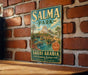A vintage metal sign for Salma Park in Saudi Arabia, featuring a scenic illustration of the park and palm trees.