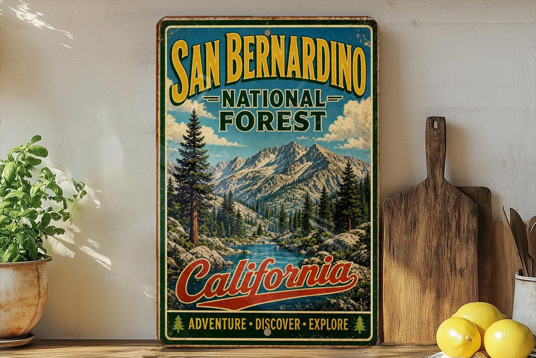 A vintage-style sign for the San Bernardino National Forest in California, featuring a scenic mountain landscape and the text "San Bernardino National Forest California Adventure - Discover - Explore".