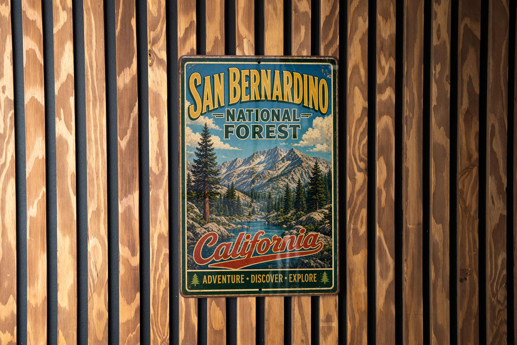 A vintage-style metal sign for the San Bernardino National Forest in California, featuring a scenic mountain landscape and the text "California" and "Adventure - Discover - Explore".