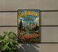A vintage-style metal sign for the San Bernardino National Forest in California, featuring a scenic mountain landscape and the text "San Bernardino National Forest" and "California Adventure - Discover - Explore".
