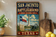 A vintage-style sign for the San Jacinto Battlefield, featuring a Texas state flag, a cannon, and a scenic landscape.