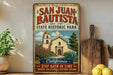 A vintage-style metal sign for San Juan Bautista State Historic Park, featuring an illustration of the historic mission church and the surrounding landscape.