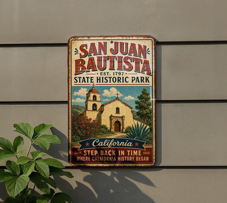 A vintage-style metal sign for San Juan Bautista State Historic Park, featuring an illustration of a historic building and surrounded by a lush green plant.