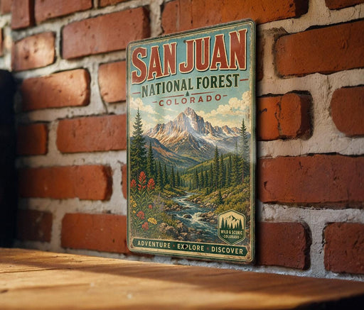 A vintage-style metal sign for the San Juan National Forest in Colorado, featuring a scenic mountain landscape with pine trees, a river, and wildflowers.