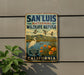 A vintage-style metal sign for the San Luis National Wildlife Refuge in California, featuring a bird, flowers, and a scenic landscape.