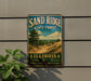A vintage-style metal sign for the Sand Ridge State Forest in Illinois, featuring a scenic landscape with a pine tree and dunes.