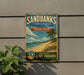 A vintage-style sign for Sandbanks Provincial Park, Ontario, Canada, featuring a beach scene with a tree and waves.