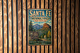 A vintage metal sign for Santa Fe National Forest in New Mexico, featuring a scenic mountain landscape.